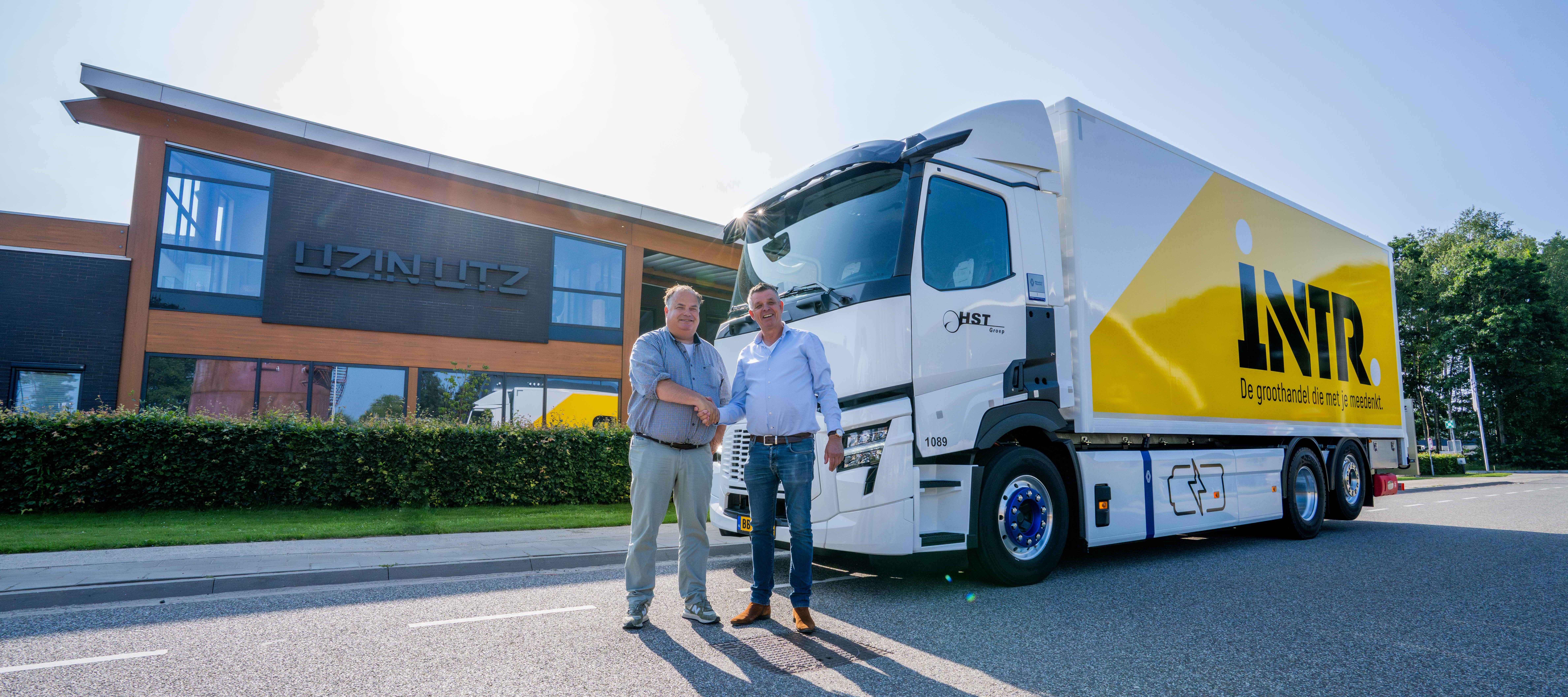 Moderner LKW mit Markenwerbung vor Firmengeb&auml;ude, zwei Personen im Gespr&auml;ch, symbolisieren Logistik und Kundenservice